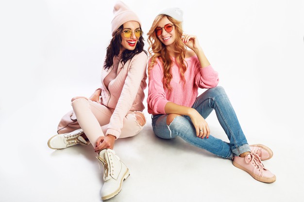 two-laughing-girls-best-friends-posing-studio-white-background-trendy-pink-winter-outfit_273443-3638